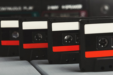 Row of vintage audio cassettes and tape recorder at gray background