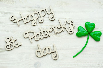 Happy St Patrick's Day wooden lettering with handmade clay shamrock over a rustic wooden background