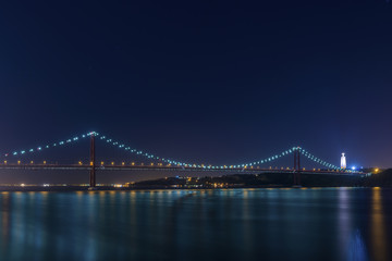 Beautiful and serene view of the Tagus River and the 25 of April Bridge (Ponte 25 de Abril) at night, in Lisbon, Portugal