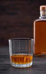 Whiskey on a  black wooden tableSilhouette of a bottle.