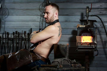 Senior blacksmith forging the molten metal on the anvil in smithy.