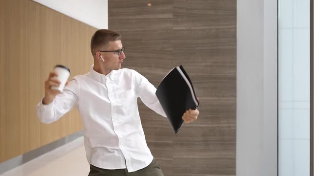 Funny Businessman With Coffee Cup Dancing In Wireless Airpods In Office Hall