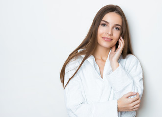beautiful young woman with long hair wearing bath robe and posing on grey background with copy space