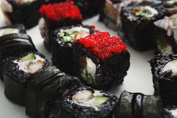 Black sushi, maki rolls with unagi sauce on white