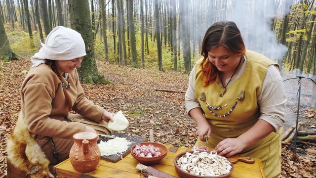 Womens viking are cooking in the forest camp. Womens talking and smiling