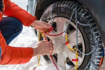man putting snow chains on car tire