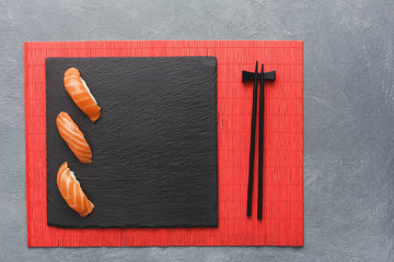 Sushi set and chopsticks on red mat, top view
