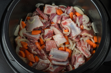 Raw meat with vegetables is cooked in a saucepan