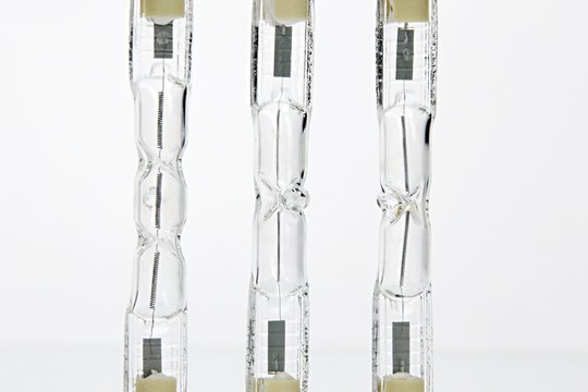 Detail of three double ended halogen J type T light bulbs on lit background
