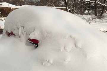 Parked car covered with thick layer of snow after blizzard in winter time