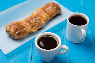 two cups of black coffee on blue boards with a twirl
