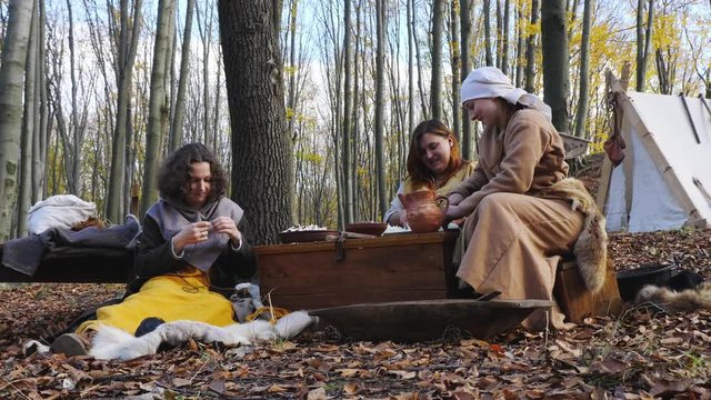 Portrait of Viking women prepare and knit in the forest camp