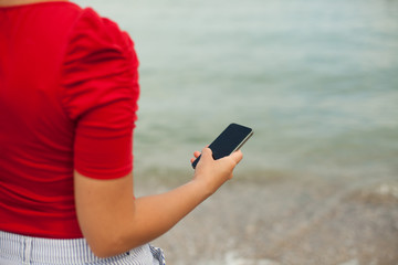 Girl using phone by the sea