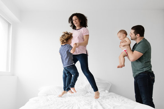 Family of four bouncing together on bed