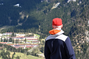 Fototapeta na wymiar Junger Mann genießt den Ausblick von der Spitze eines Berges auf ein Dorf im Tal