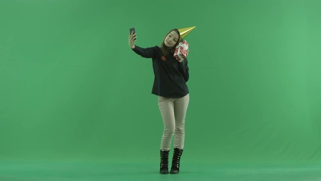 Young woman takes selfie with her birthday present, green chroma key background