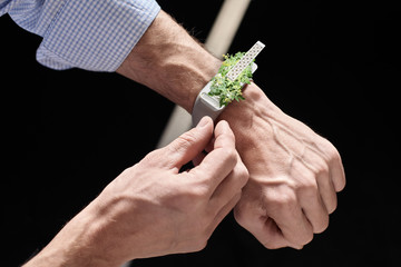 Man setting up smartdevice. Man's hand setting up smart watch on his hand, concept smart device with potted plant