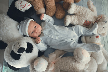 newborn baby laying with five teddy bears on blanket