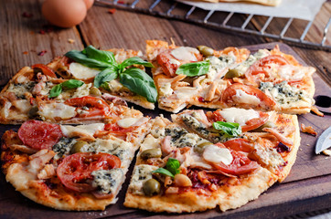 Cut into slices delicious pizza on wooden table, still life