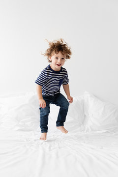Happy little boy bouncing on bed