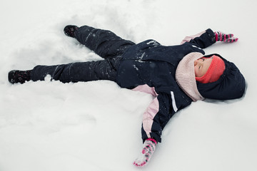 Fototapeta na wymiar The kid is lying in the snow on the ground