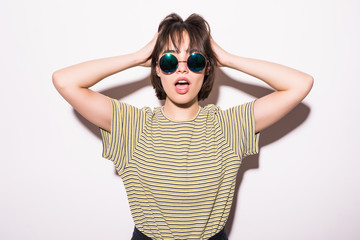 Portrait of a shocked young girl sunglasses looking at camera with open mouth isolated over white background