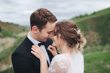 Beautiful newlyweds. Wedding. The groom looks at the bride and touches her forehead. A great spring day.