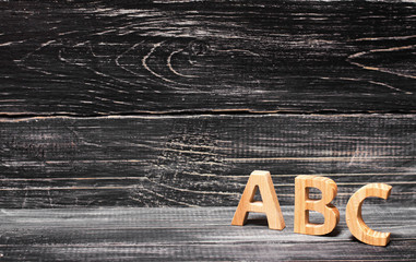 Alphabet made of wood on the background of a board, ebony. Concept of education, English. English letters, retro.