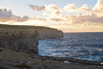 Fototapeta na wymiar Rocky cliffs in the afternoon light on the coast of Gozo, an island of Malta