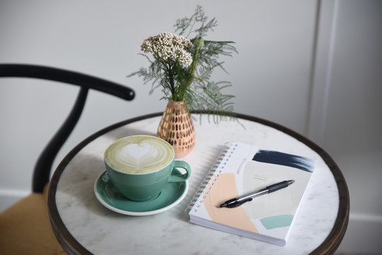 Coffee, diary and pen with flower bouquet on table