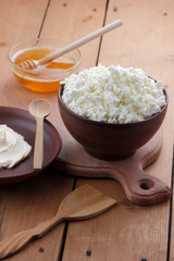 Cheese, fresh cheese and sour cream in pottery, honey, goat cheese for breakfast, healthy eating, healthy dairy products, cheese and cream in rustic style, minimalist, copy space, wooden board