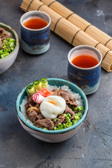 Rice and beef bowls with tea, concrete background