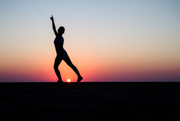 Fototapeta premium A silhouette of a girl dancing front of a sunset