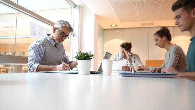 Teacher meeting around table with students 