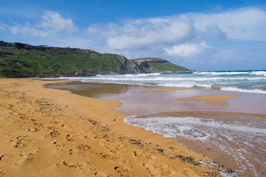 Waves wash over Ramla Beach on the island of Gozo, Malta