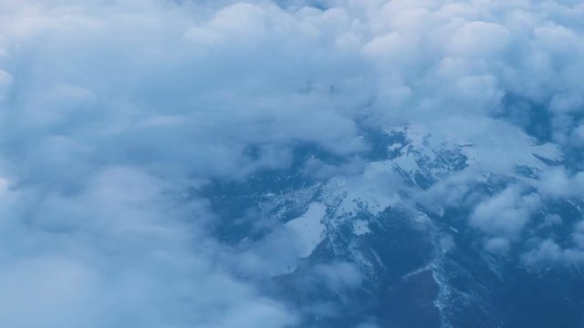 View from the airplane window on a snowy mountains and clouds, 4k.