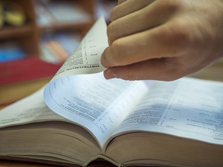 Fototapeta premium close up hand turning the page of book on the table