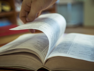 Obraz premium close up hand turning the page of book on the table