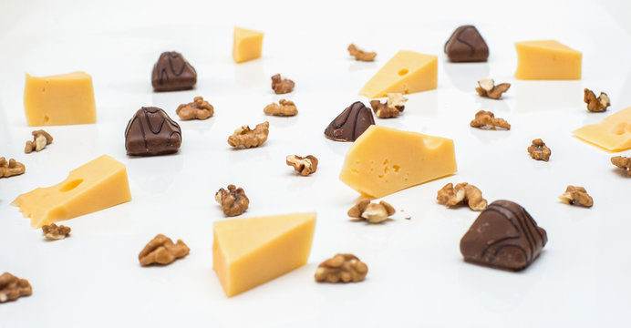 Pieces of cheese with Greek nuts on a light paper background. chocolate candy