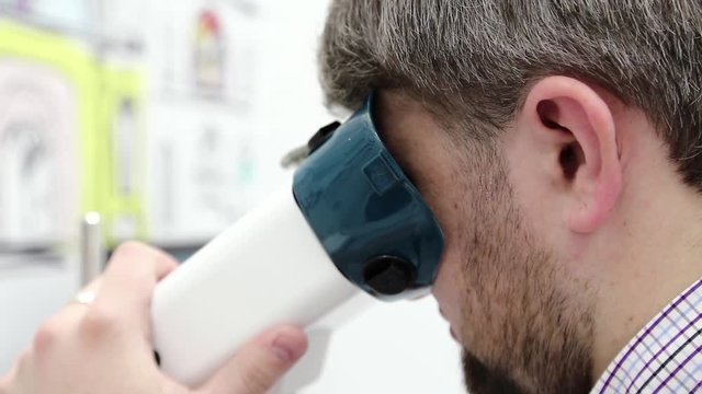 Patient in ophthalmology clinic. Man looks in apparatus for the treatment of spasm of accommodation, amblyopia and binocular vision disorders