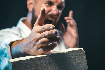 Bearded man breaking the concrete slab with his hand. Bearded man do karate training. Strong,...