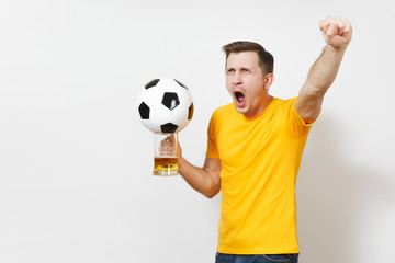 Inspired young fun cheerful European man, fan or player in yellow uniform hold pint mug of beer, soccer ball cheer favorite football team isolated on white background. Sport, play, lifestyle concept.