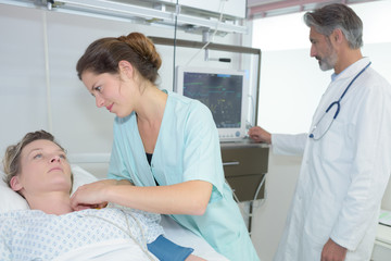 Obraz premium attentive young doctor consulting middle age female in bed