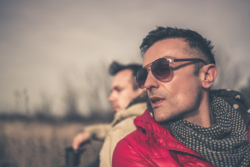 Gay male couple sitting down in grass talking