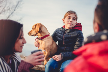 Family with dog sitting at a picnic table and talking