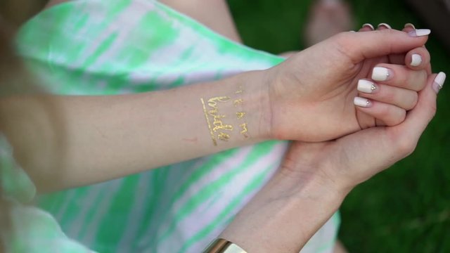 Woman with golden tattoo bride team at hand