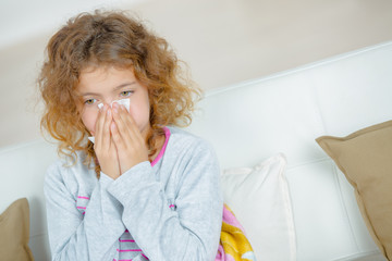 Young girl blowing nose with tissue