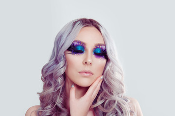 woman with artistic purple blue eyes makeup feather on eyelashes touching face with hand