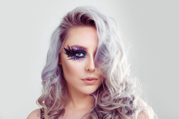 Beautiful woman with artistic purple blue eyes makeup feather on eyelashes and curly hair © hbrh