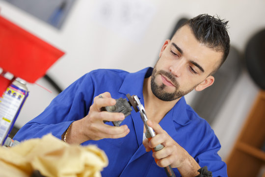 mechanic cleaning auto part in the workshop